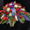 A broad, low casket spray crafted in a bold red, white, and