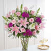 Pink lilies and roses arranged in a clear glass vase
