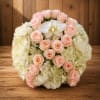 Round bouquet of pale pink roses and white hydrangeas with a white orchid center