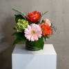 Small bouquet of orange roses and a pink gerbera daisy in a glass vase