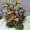 Tropical floral centerpiece with pink roses and lilies around a silver urn