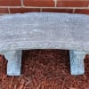 Decorative stone bench with an engraved quote in a garden bed
