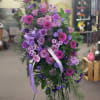 Standing spray of purple and pink flowers with lavender ribbons