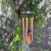 Copper wind chime hanging from a tree branch