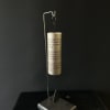 Gold wind chime hanging from a metal stand on a dark base