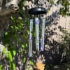 Hanging black wind chime with floral tubes and a tag