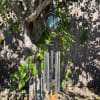 Stained-glass and metal wind chime hanging from a tree branch