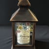 Bronze lantern with a memorial candle and pastel floral print