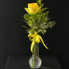 Yellow rose in a clear glass vase with a yellow ribbon