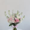 Pink and white bouquet in a clear glass vase with a pink ribbon