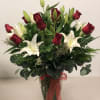 Red roses and white lilies in a clear glass vase with a red ribbon