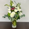 White roses and hydrangeas with green accents in a clear glass vase