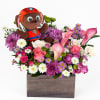 Plush puppy in a flower arrangement with pink calla lilies and mixed blooms in a wooden box