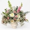 White and pink floral arrangement in a cream vase