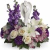Purple and white floral arrangement with an angel figurine centerpiece