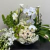 White orchids, calla lilies, roses, and green blooms in a low arrangement