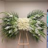 Large white floral spray with roses and lilies on an easel
