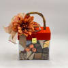 Gift box of assorted chocolates topped with an orange flower and ribbon