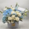 White roses and blue orchids arranged in a round hat box with a "It's a Boy" topper.