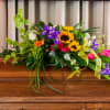 Colorful floral casket spray with sunflowers, roses, and orchids