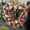 Large heart-shaped floral wreath with pink and white flowers on a stand