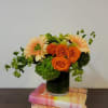 Orange roses and pale peach gerbera daisies in a glass vase