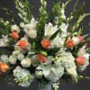 Large white floral arrangement with orange roses in a white vase