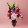Bouquet of red roses, pink lilies, and pale hydrangeas in a red glass vase