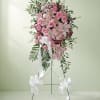 A heartfelt tribute of soft pink roses and lilies flows gracefully, honoring