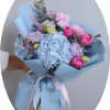 A pale blue hydrangea anchors this romantic spring bouquet, paired with pink