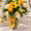 Yellow and white bouquet in a clear glass vase with an orange ribbon