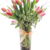 Pink tulips arranged in a tall glass vase with a ribbon