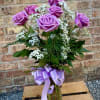 6 beautiful lavender roses are arranged in a vase with filler flowers