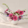 Pink gerbera daisies and mixed blooms in a white vase