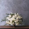 White rose and hydrangea arrangement in a gold pedestal vase