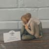 Small figurine of two people hugging beside a sympathy card
