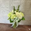 Several large white and pale green hydrangea blooms in a clear glass