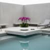 Purple orchids in a white bowl on a modern patio by a pool