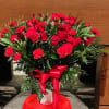 Red roses and carnations arranged in a vase with a red ribbon