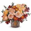 Autumn bouquet of peach roses and orange mums in a rustic wood vase