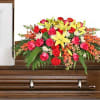 Bright floral spray arranged on a wooden casket