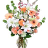 Peach and white flower bouquet in a clear glass vase