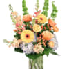 Mixed bouquet of peach and yellow flowers in a clear glass vase