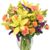 Bouquet of yellow lilies, orange roses, and pink carnations in a glass vase