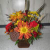 Orange and red mixed flower arrangement in a brown basket