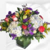 Mixed bouquet of roses, hydrangeas, and purple flowers in a square vase