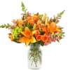 Orange lilies and roses arranged in a clear glass vase