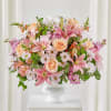 Pink lilies, peach roses, and white daisies in a white pedestal vase