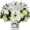 White lilies and roses arranged in a clear glass vase