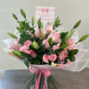 Pink roses and lily buds in a wrapped bouquet with a pink ribbon
